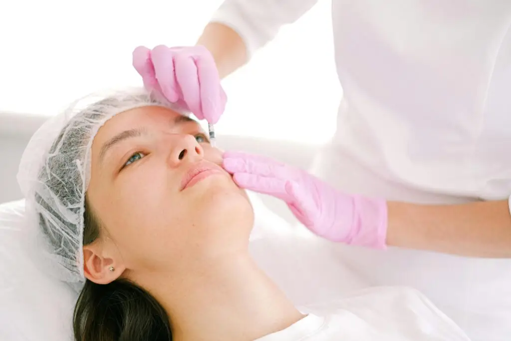 About Woman receives cosmetic injection in clinical setting, enhancing beauty using modern techniques.