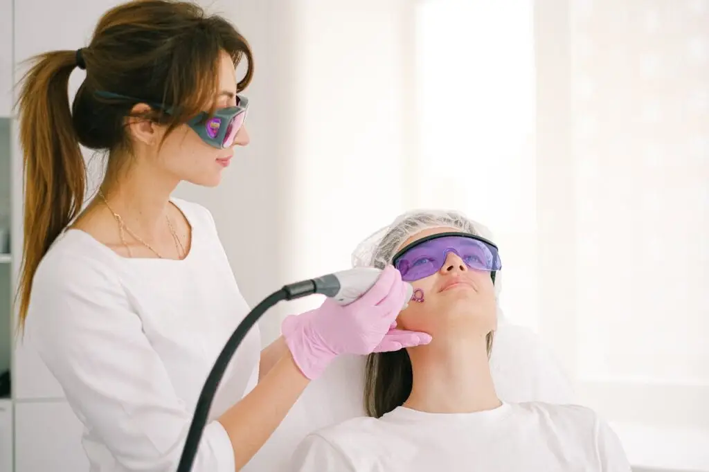 About A cosmetologist performing laser treatment on a woman in a clinic setting.